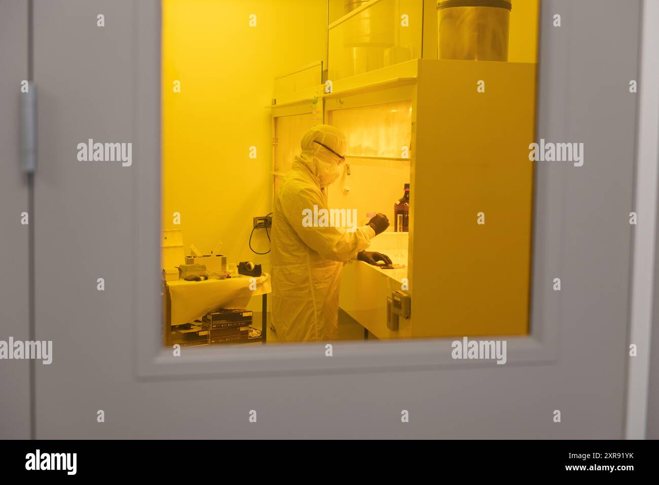 Scientist working in yellow light clean room in full PPE bunny suit Stock Photo - Alamy
