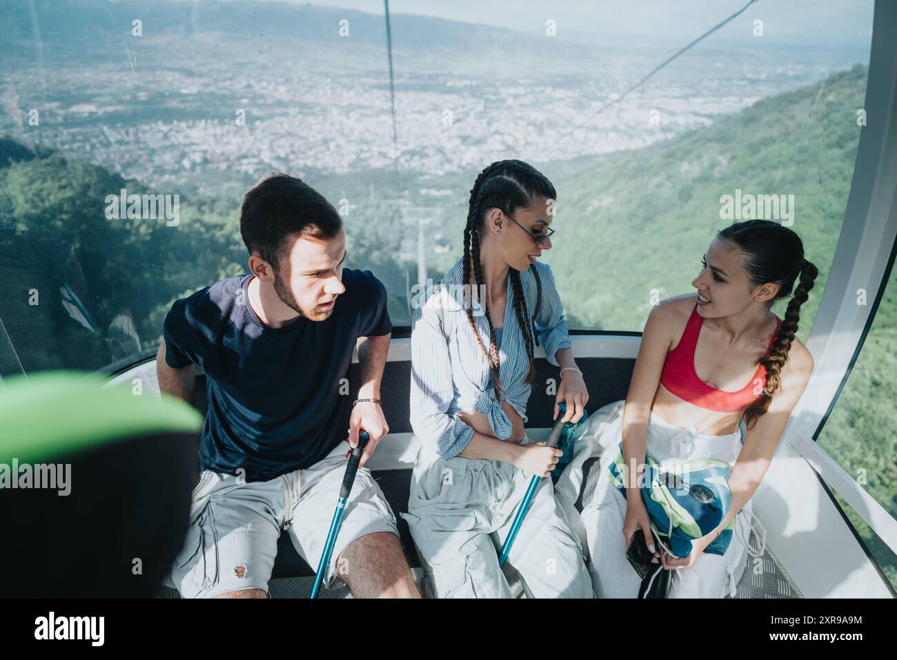 Three friends enjoying a cable car ride with a scenic mountain view ...