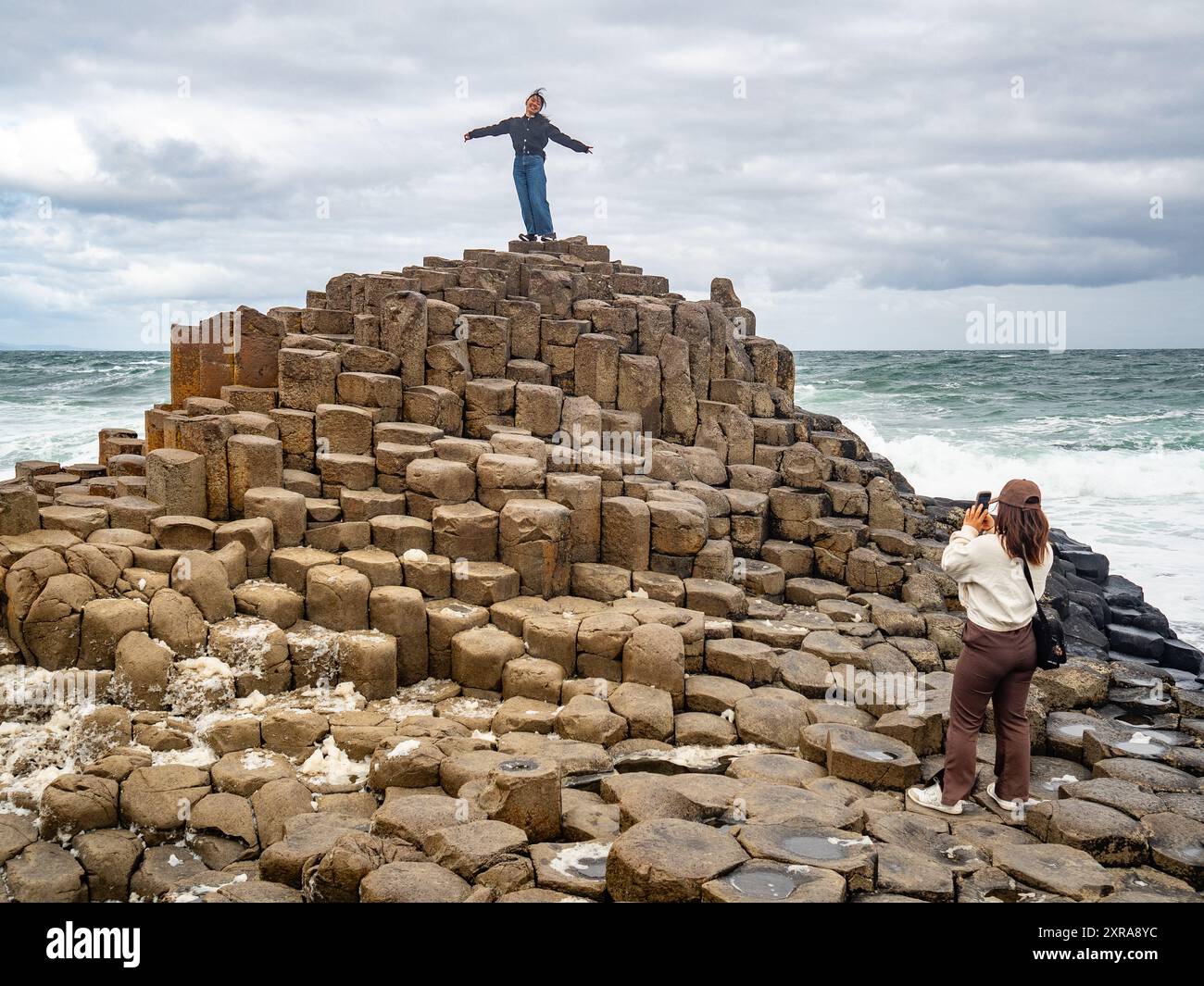 Tourists walking among the hexagonal basalt columns of the Giant's Causeway near Bushmills at sunset