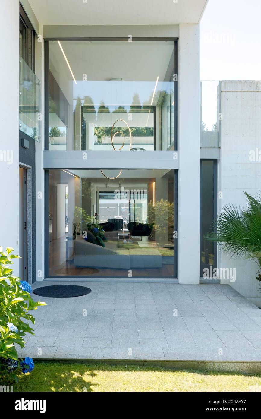 Detail of the entrance of a white modern house with large windows, from  which you can see through the entire house. Sunny summer day and blue sky.  No Stock Photo - Alamy, image size:866x1390