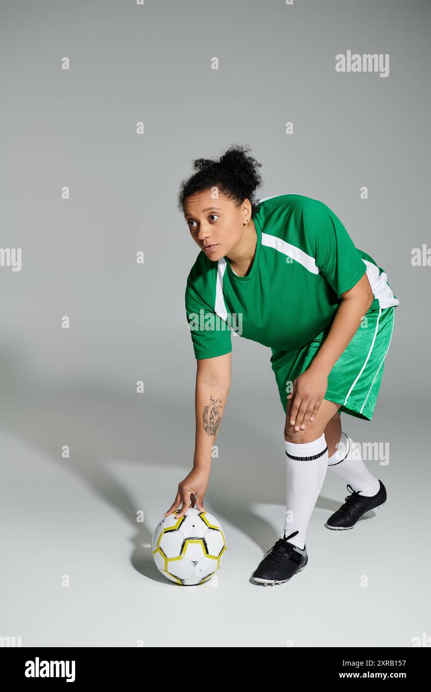 A female athlete in green sportswear prepares to play football on a ...