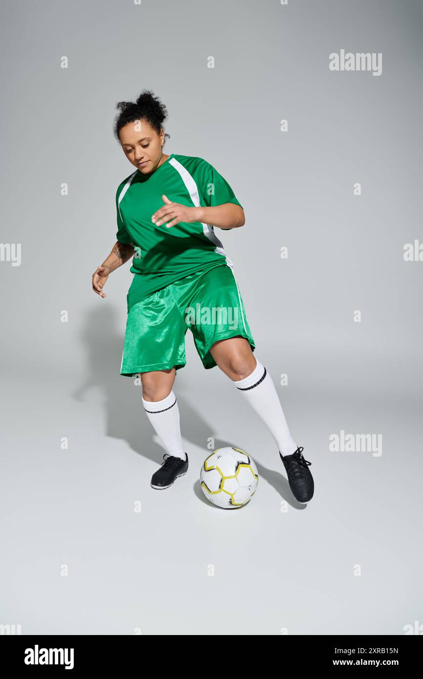 A female athlete in a green jersey dribbles a soccer ball in a studio ...