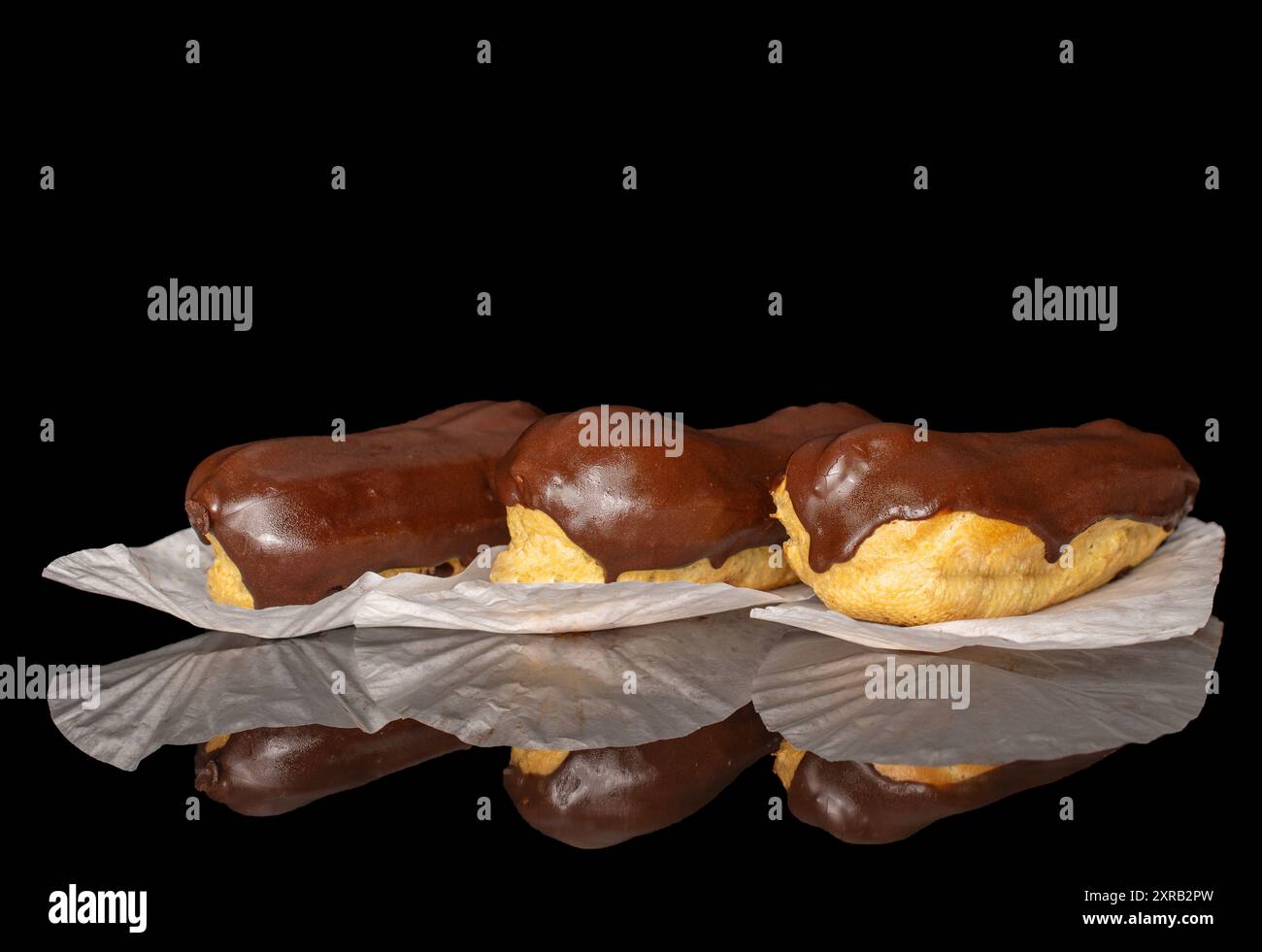 Three eclairs with cream, macro, isolated on a black background. Stock Photo