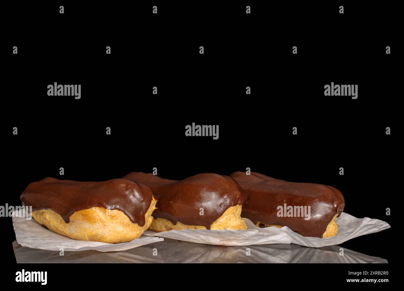 Three eclairs with cream, macro, isolated on a black background. Stock Photo
