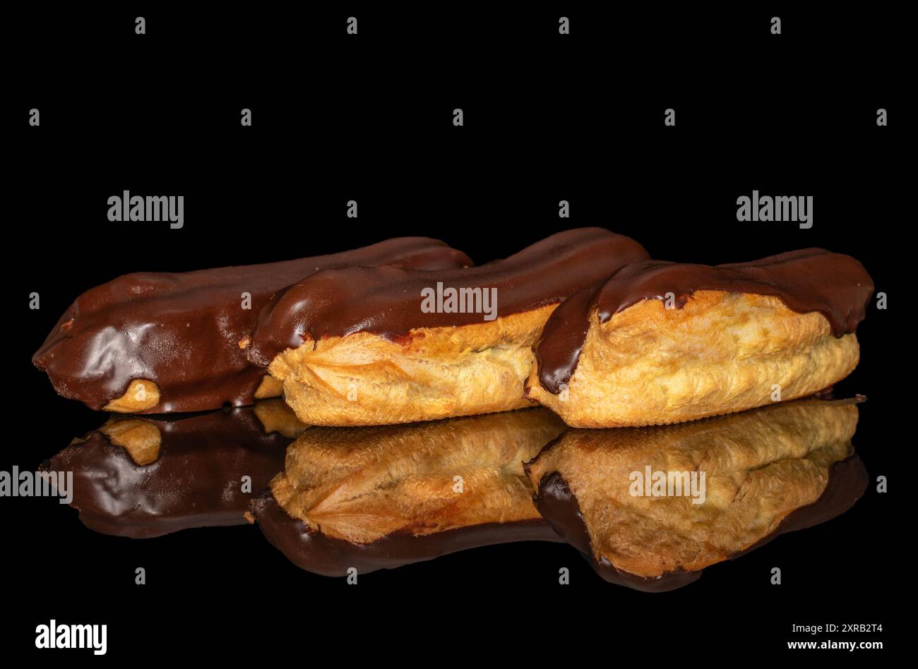 Three eclairs with cream, macro, isolated on a black background. Stock Photo