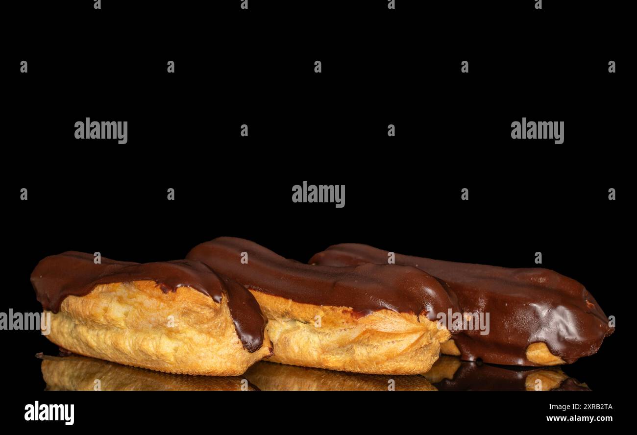 Three eclairs with cream, macro, isolated on a black background. Stock Photo