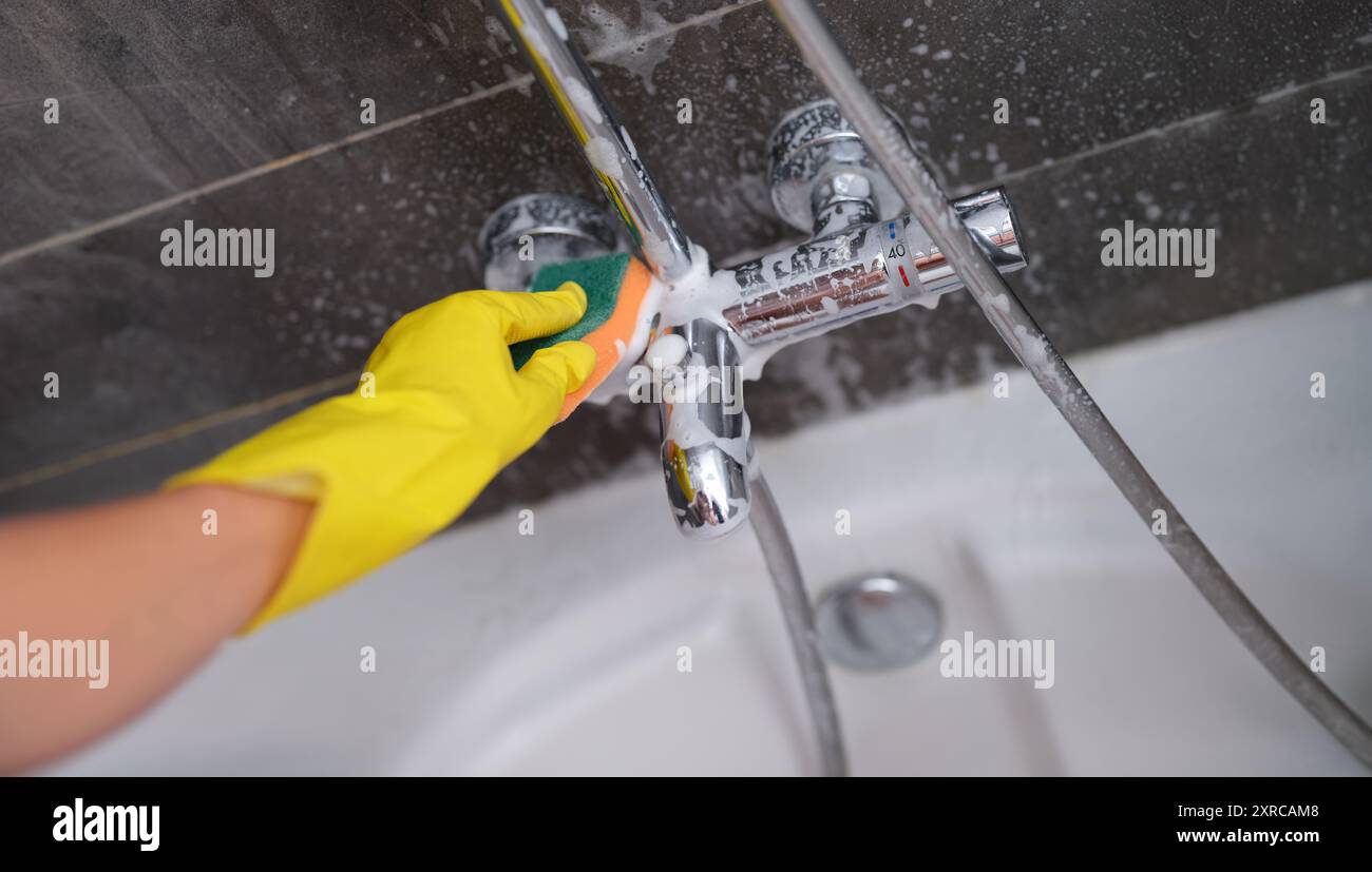 A hand in a yellow glove washes the mixer in the bathroom Stock Photo ...