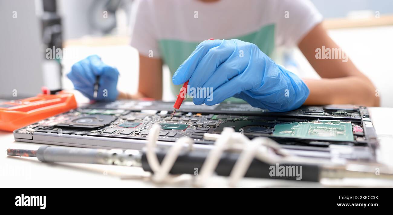 Repairman hands hold screwdrivers over laptop processor Stock Photo