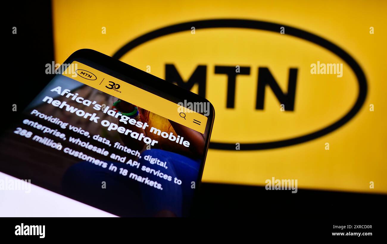 Mobile phone with website of South African telecommunications company MTN Group Limited in front of logo. Focus on top-left of phone display. Stock Photo