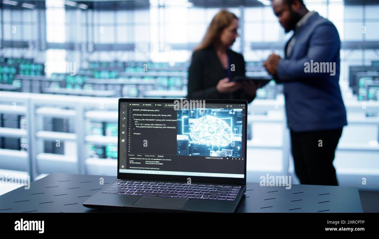 Laptop in data center establishment with artificial intelligence computing simulating human brain. Close up shot of notebook displaying AI machine learning algorithms, camera B Stock Photo