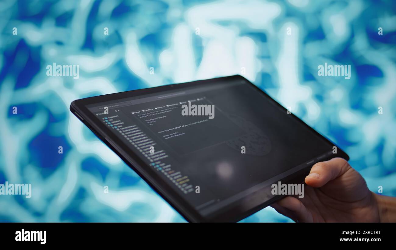 Software developer with tablet programming artificial intelligence computing simulating human brain. Close up of IT professional using device, building AI machine learning algorithms, camera B Stock Photo