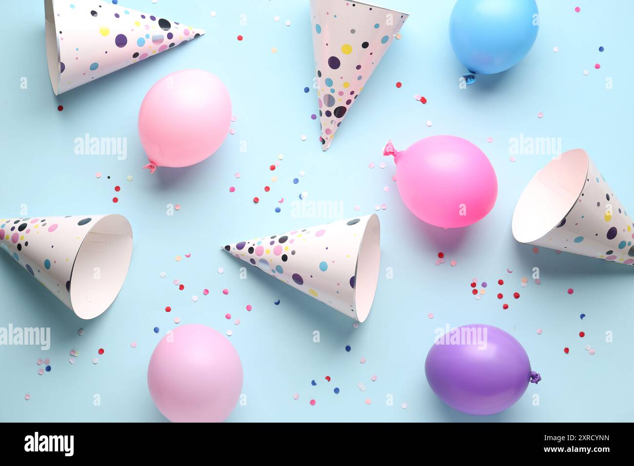 Party hats and balloons on pale blue background Stock Photo - Alamy