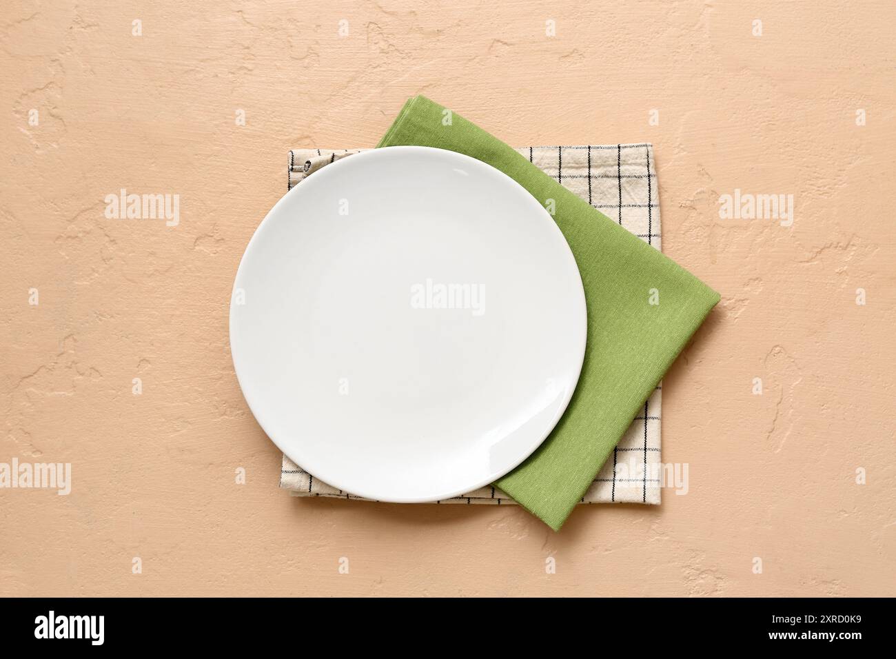 Table setting with plate and napkins on beige background Stock Photo