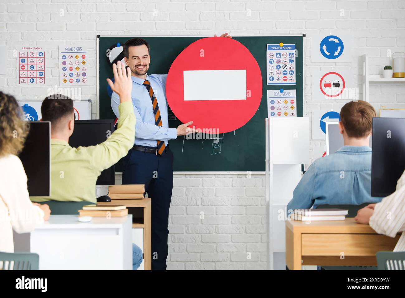 Male instructor with road sign giving lesson to people at driving ...