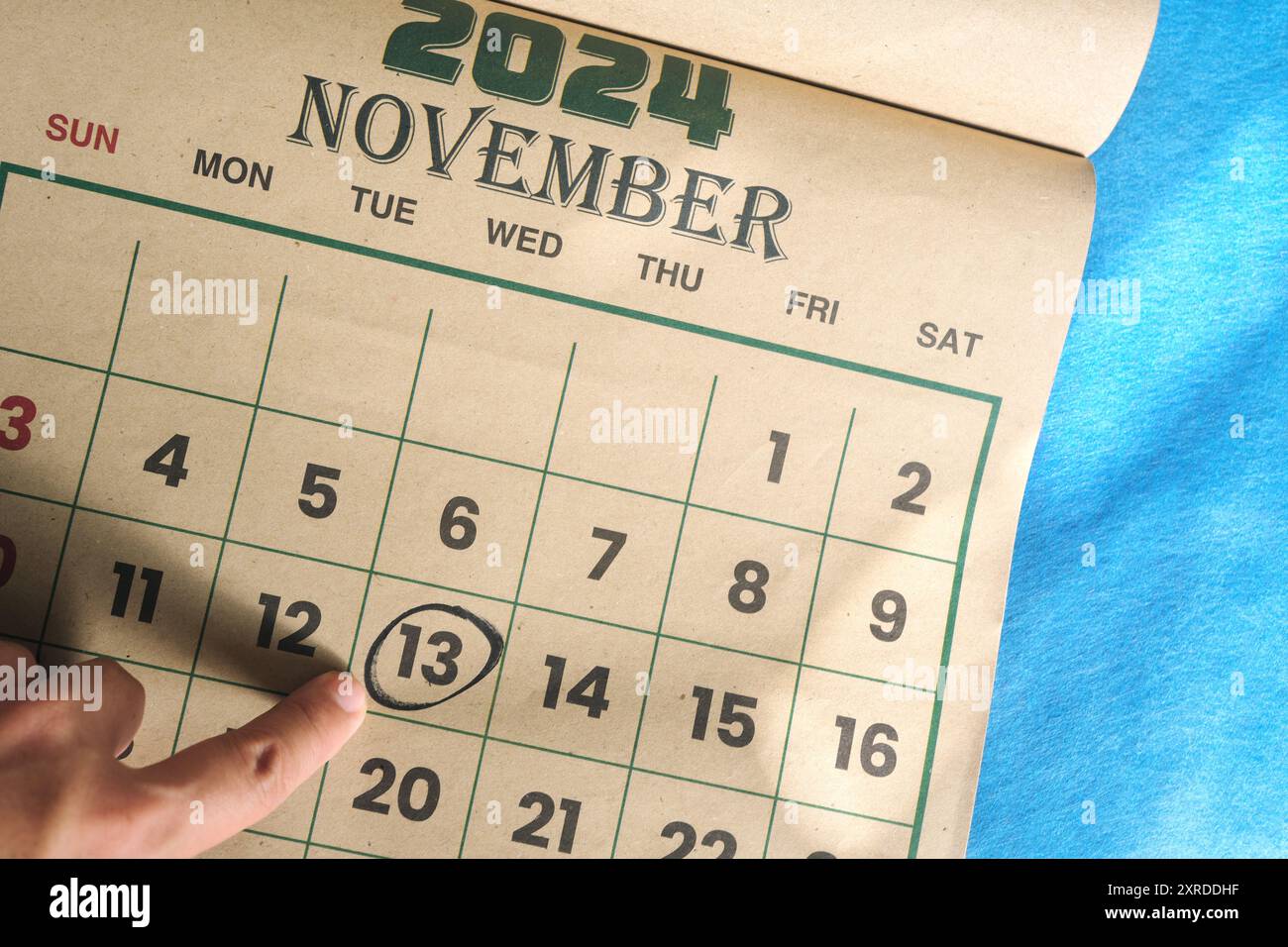 Hand pointing on November 13 2024 date on calendar flat lay in blue background. World Kindness Day. Stock Photo