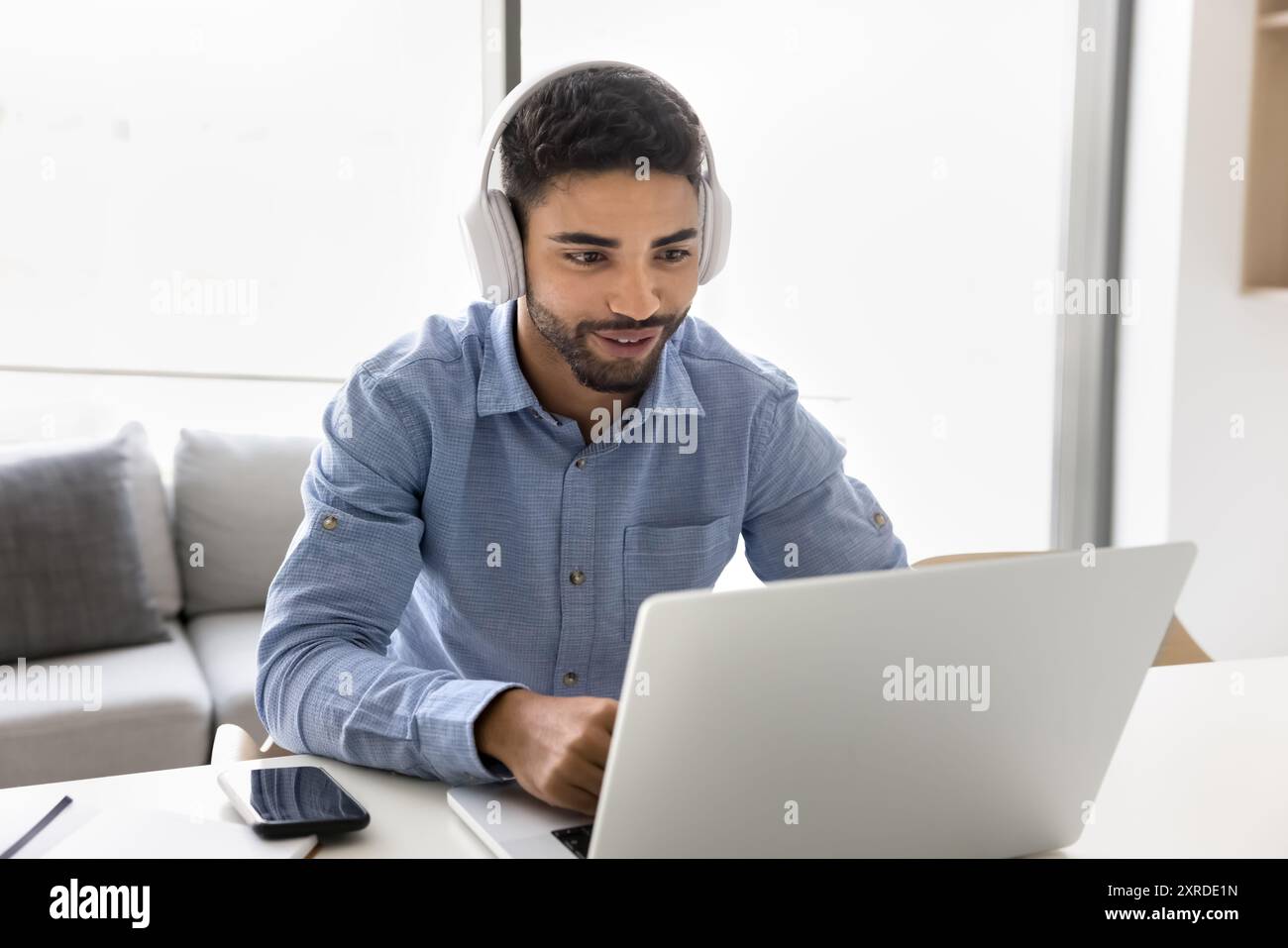 Positive Arab student guy in wireless headphones watching learning webinar Stock Photo