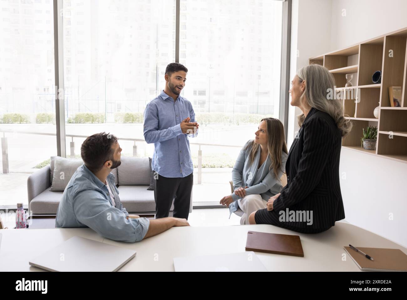 Positive young Arab project manager man talking to colleagues Stock Photo