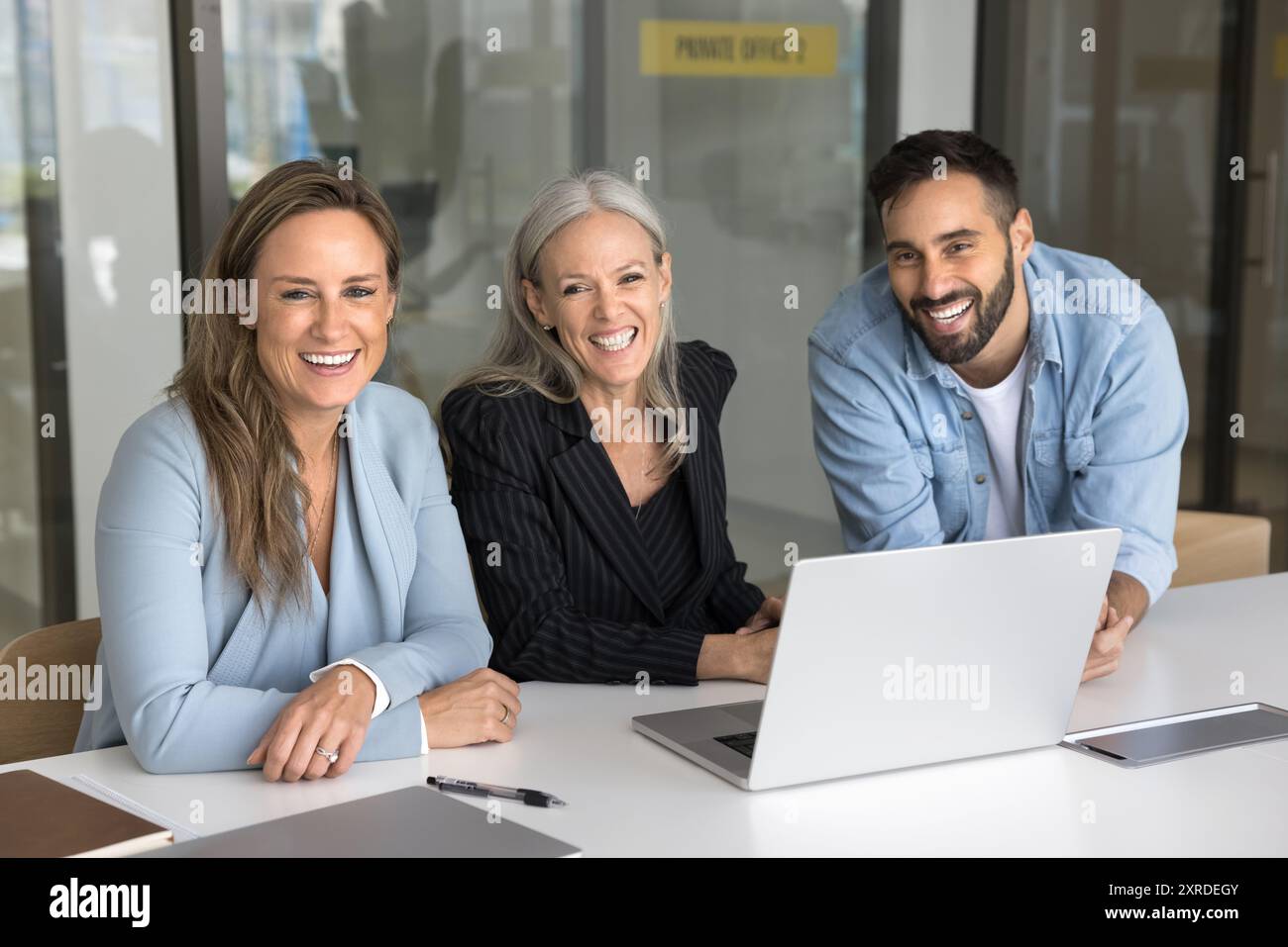 Successful team of three business colleagues sitting at workplace table Stock Photo