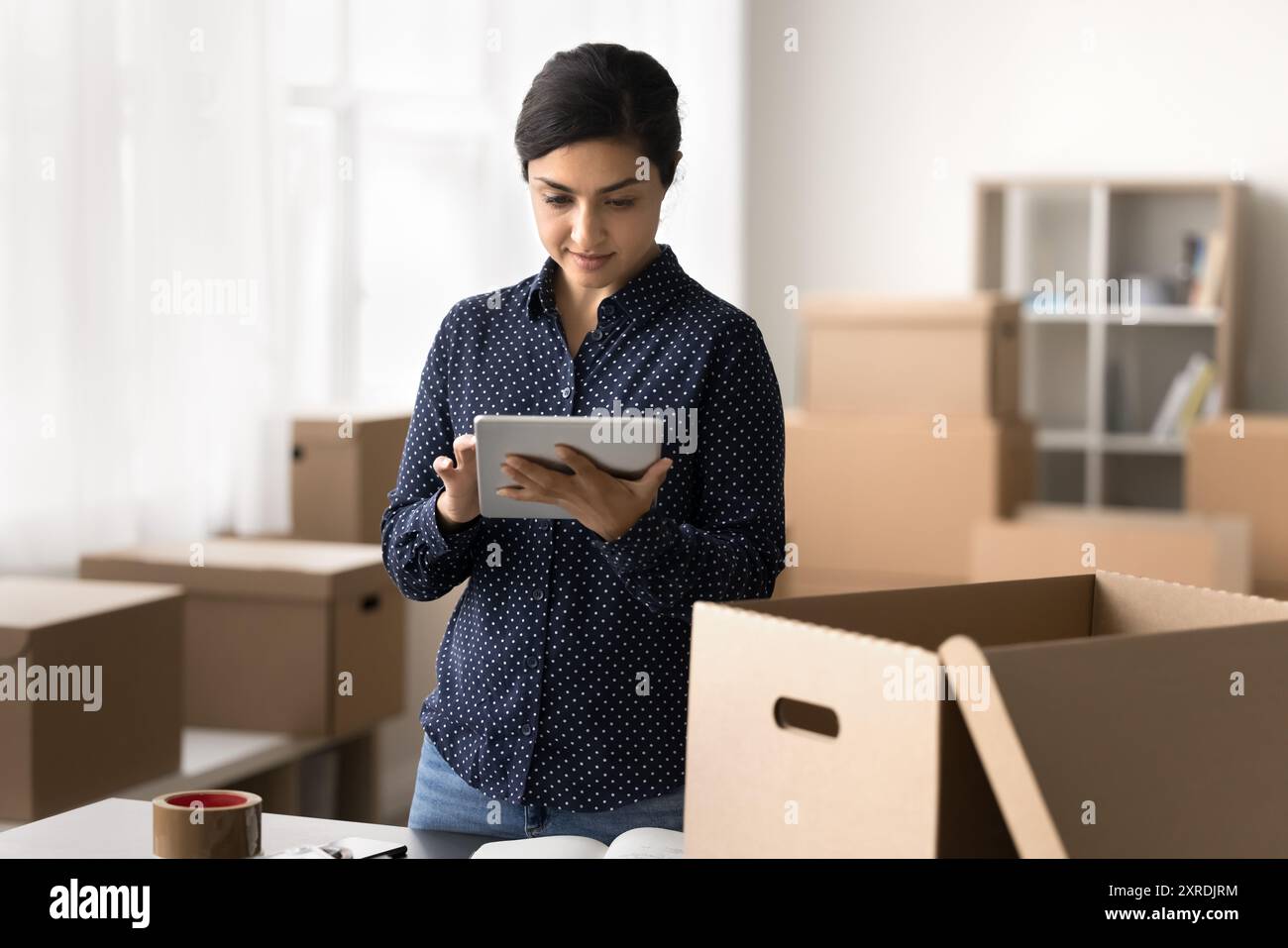 Serious Indian warehouse worker hold digital tablet Stock Photo