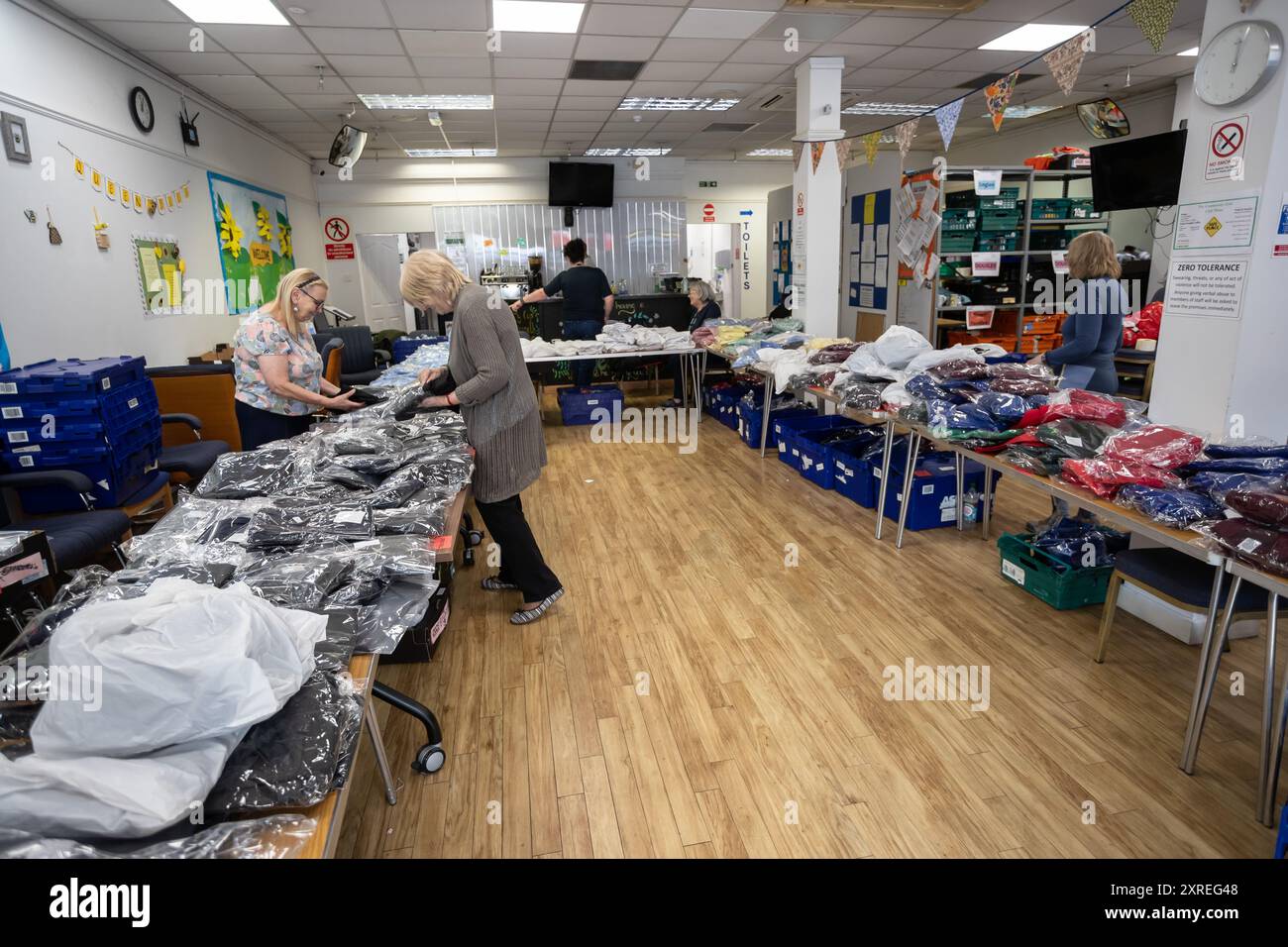 Cradley Heath, West Midlands, UK. Saturday 10th August, 2024. Volunteers prepare thousands of secondhand school uniforms ready to handout in a community centre in Cradley Heath, a economically struggling area in the Black Country, West Midlands. The local school uniforms are donated, washed, wrapped and given out to local people to re-use to help with the cost of living crisis. Credit: Peter Lopeman/Alamy Live News Stock Photo