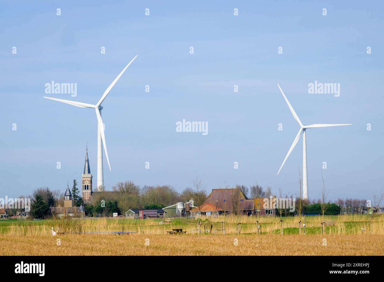 Modern windmill for renewable energy towering above an old town with an old church, Netherlands. Stock Photo