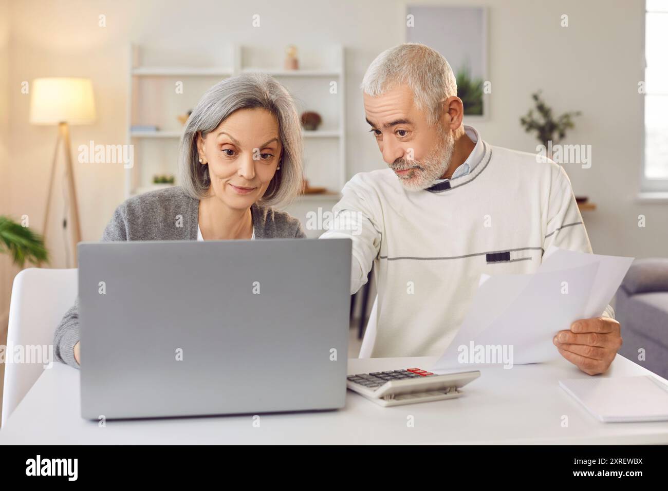Mature couple immersed in management of their home budget using modern technology. Stock Photo