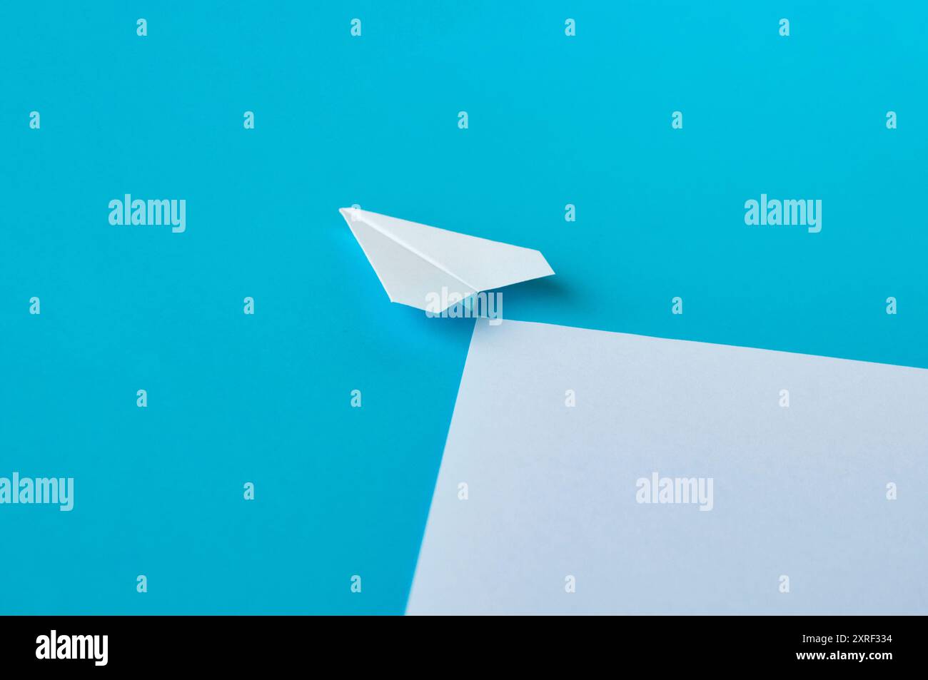 Angle view of white paper airplane flying along the route on blue ...