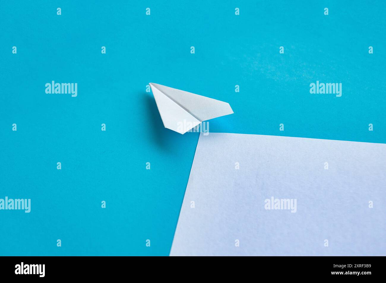 Angle view of paper airplane flying on blue background with ...