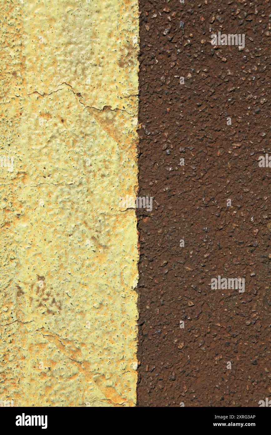 An old asphalt surface, background. Detailed texture of the darkened bitumen close-up. Brown asphalt with a yellow dividing strip.Rufous asphalte Stock Photo