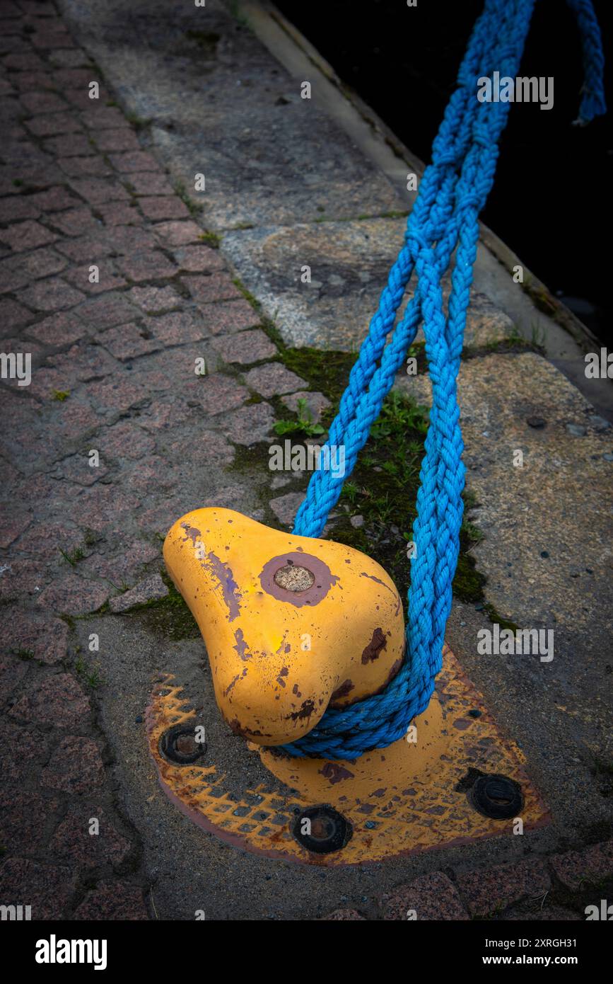 Yellow metal dock mooring pole with rope for securing fishing boats ...