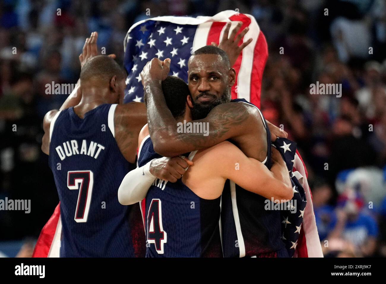 United States' Stephen Curry, center, hugs United States' LeBron James ...