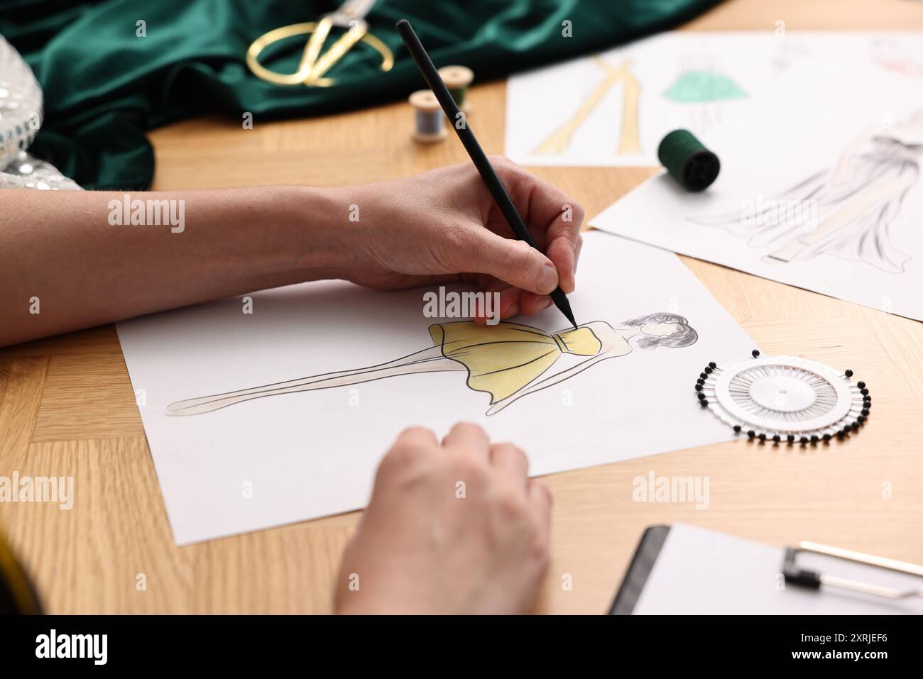 Fashion designer drawing sketch of beautiful dress at wooden table ...