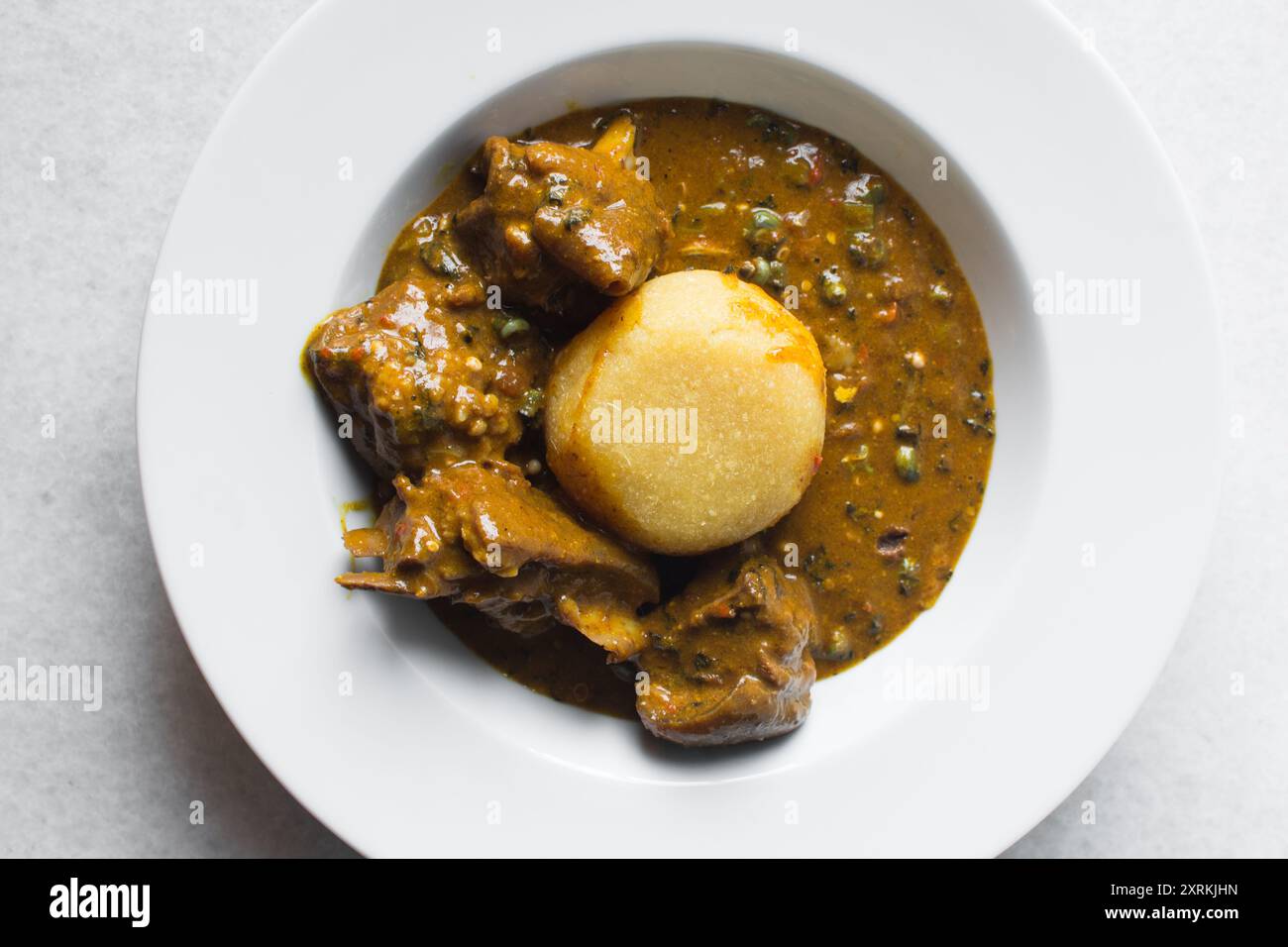 Overhead view of nigerian ogbono soup and eba on a white plate, top ...