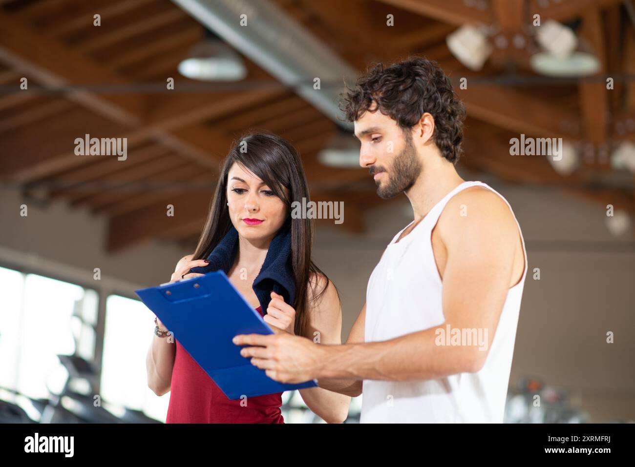 Personal trainer showing schedule to woman in a gym Stock Photo - Alamy