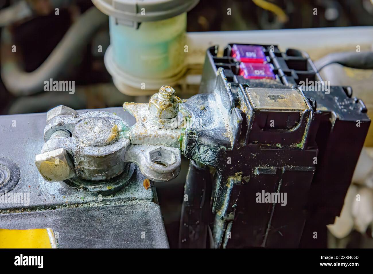 A corroded battery terminal on a battery in a car. The terminal is white with corrosion. Closeup
