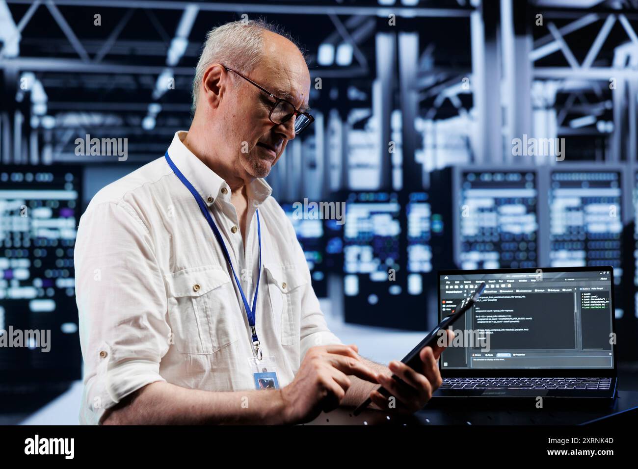 Elderly technician coding in high tech data center using javascript language. Certified specialist updating software on server rigs on laptop terminal, ensuring optimal performance and security Stock Photo