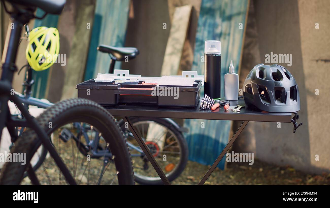 View of professional toolbox placed on table near other tools and helmet ready for bike maintenance outdoors. In yard close up of different specialized tools and bicycle helmet positioned on table Sto...