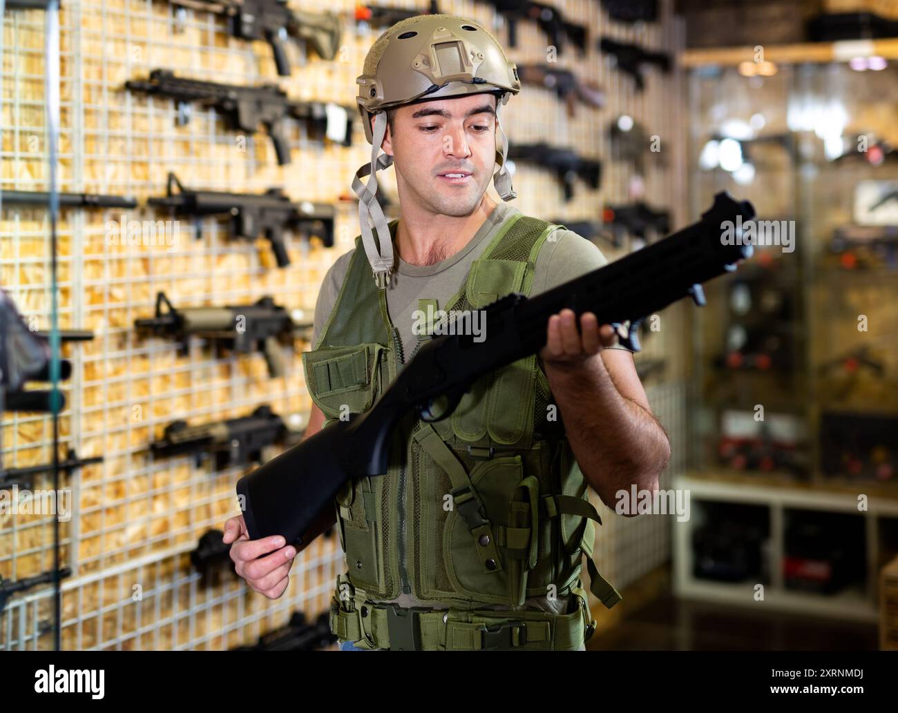 Man in armor vest selecting machine gun in air weapon shop Stock Photo ...