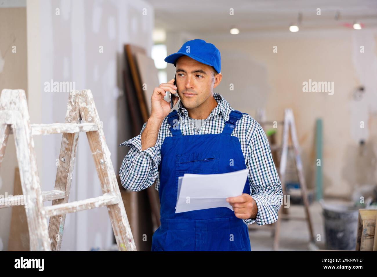 Young foreman with documents in his hands is talking on a mobile phone Stock Photo
