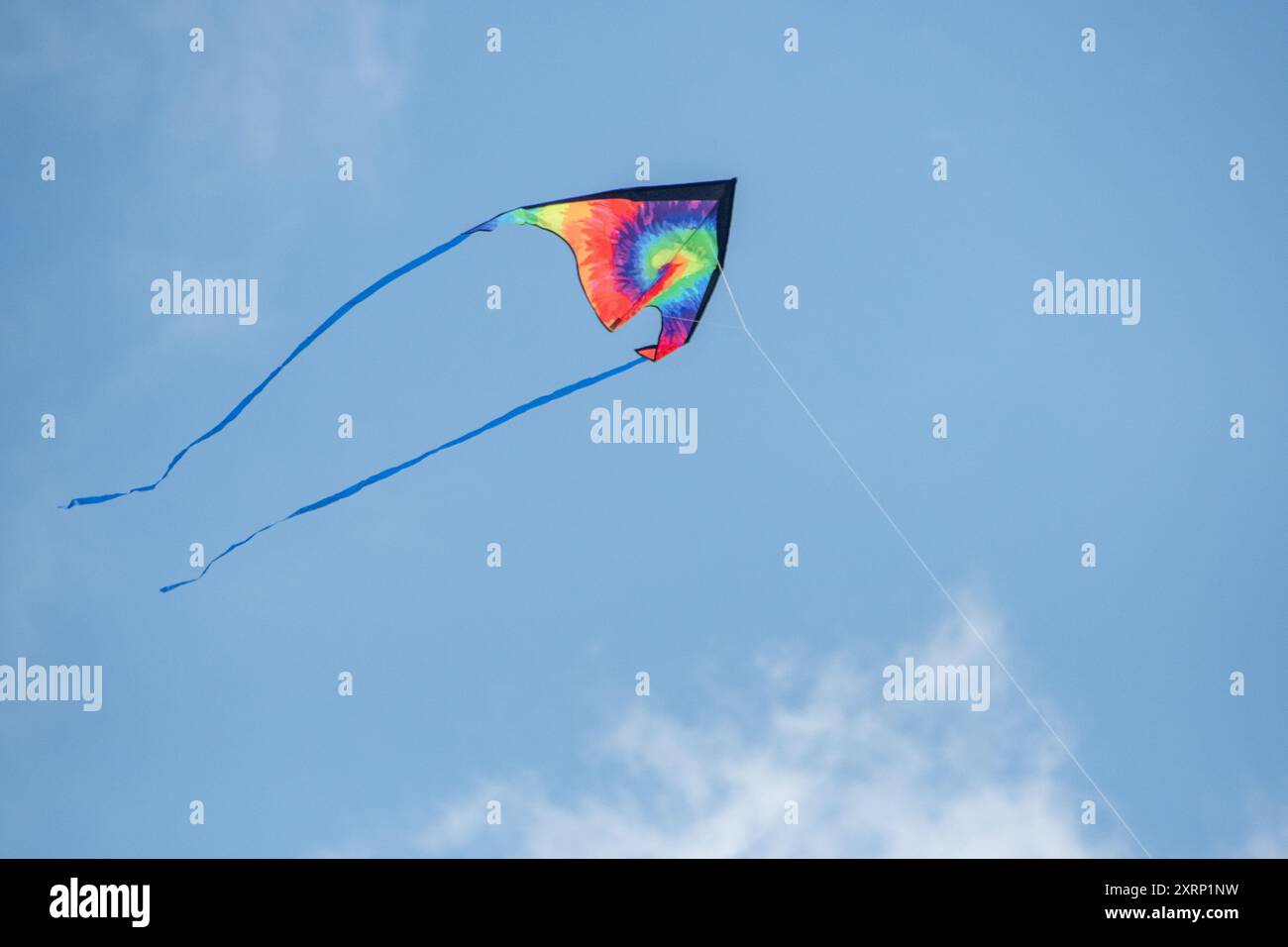 Rainbow tie dye kite flying in the sky Stock Photo