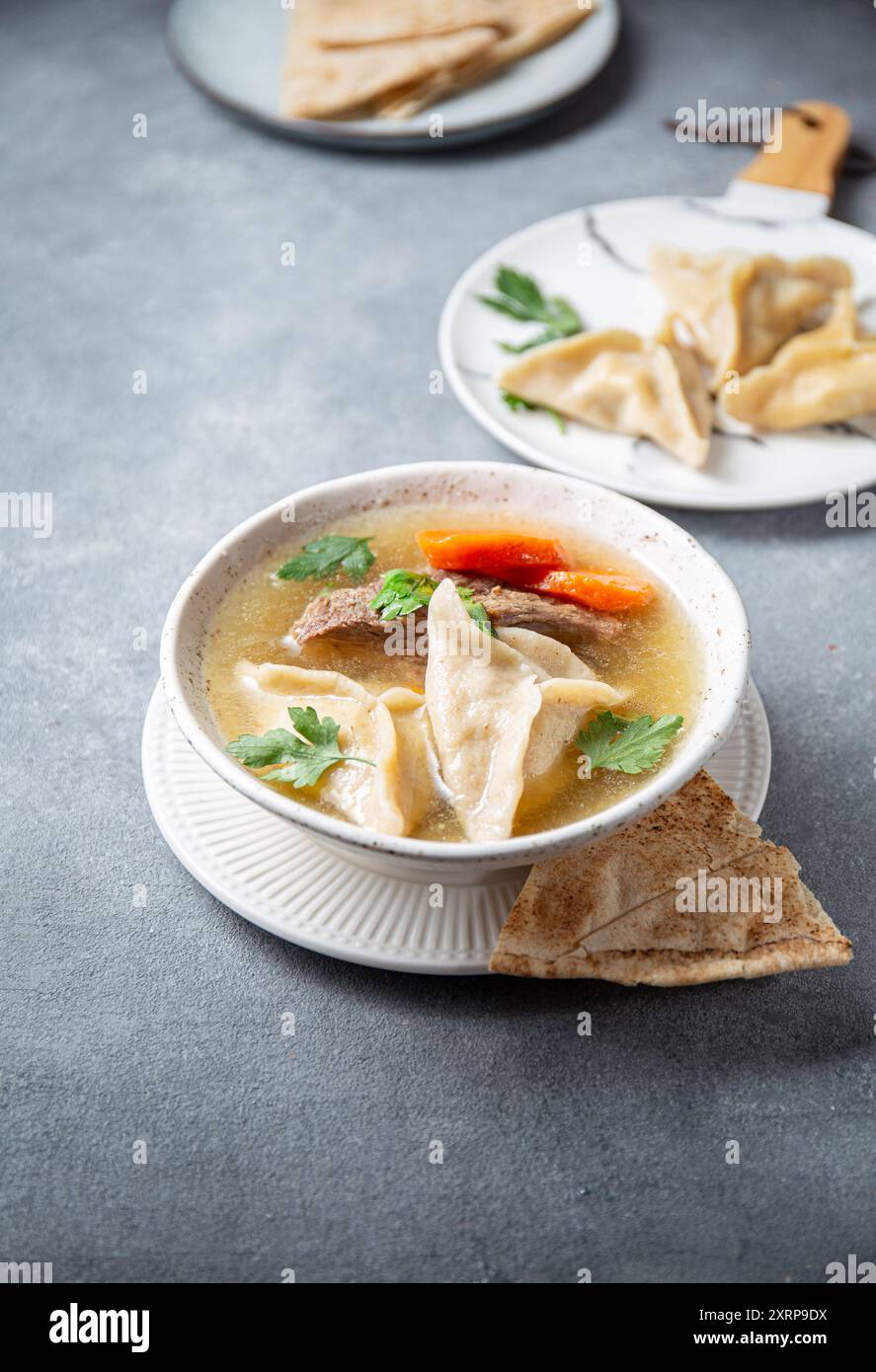 Traditional Jewish Kreplach soup with meat and carrot, gray background ...