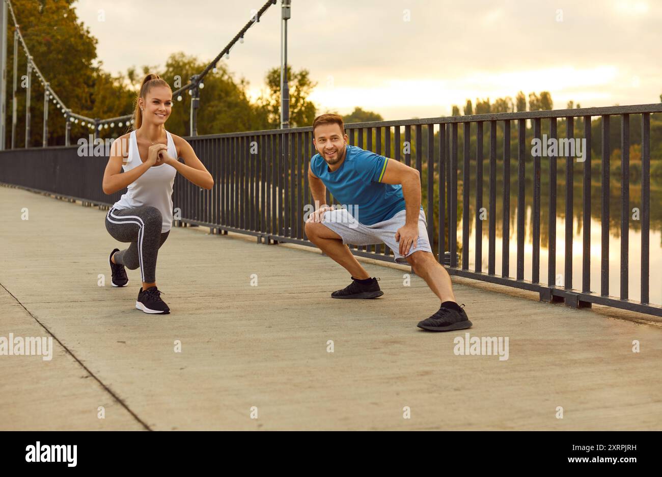 Couple in sportswear doing stretching on a bridge, close-up Stock Photo