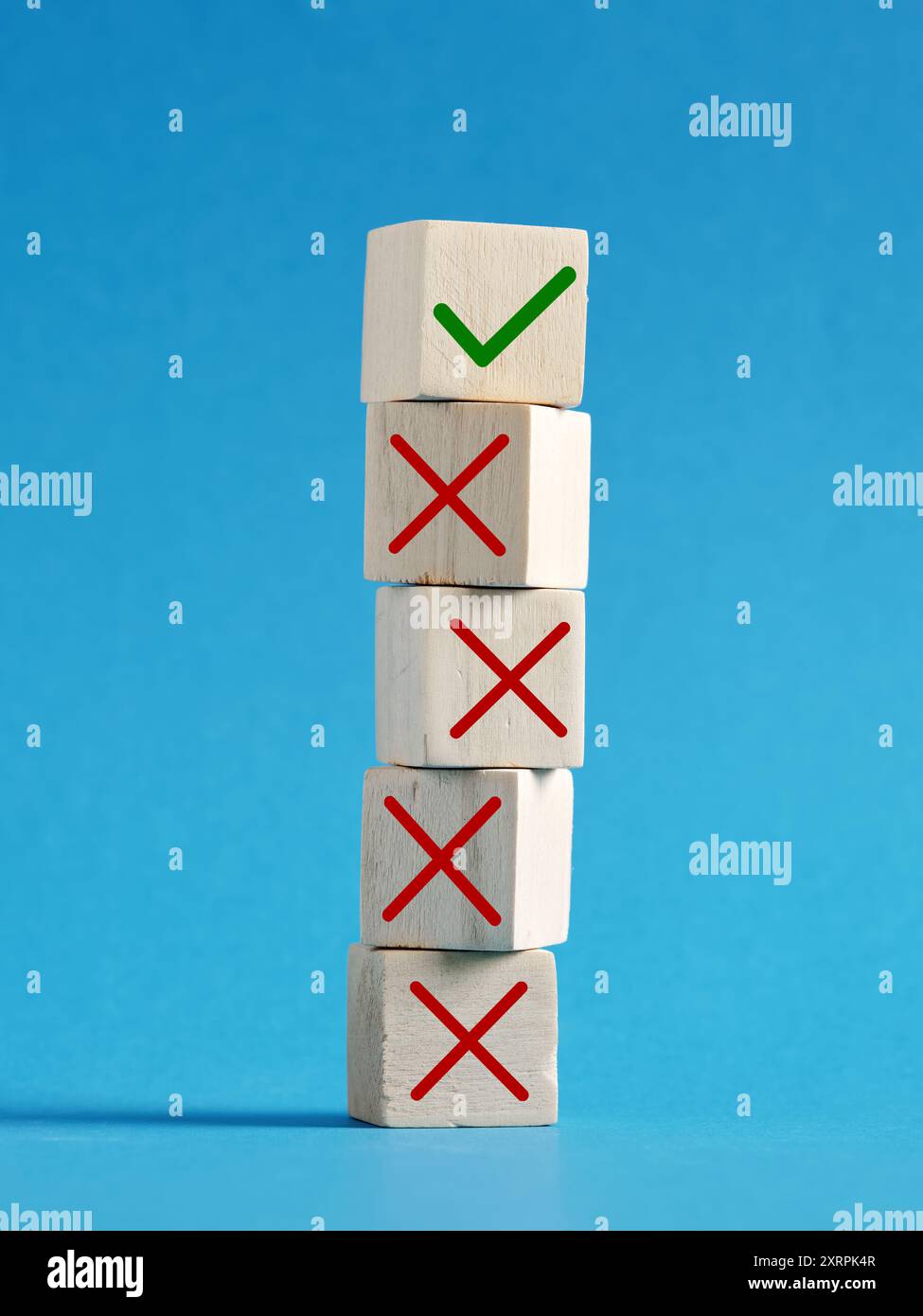 Making the right decision after wrong ones. Stack of wooden cubes is showing one right choice against many wrong ones over a blue background. Stock Photo