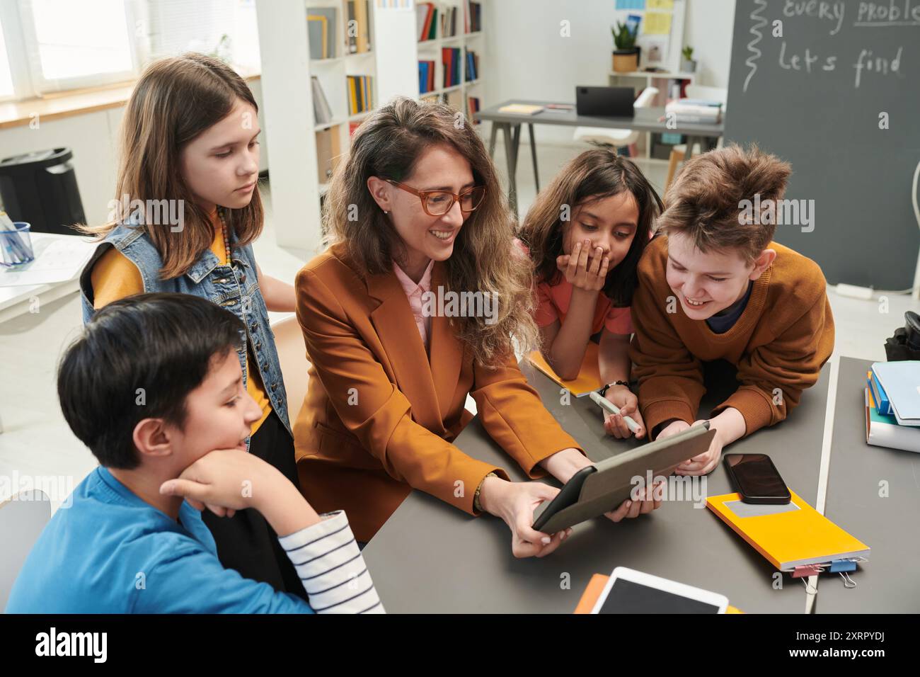Smiling Female Teacher using Tablet with Kids Stock Photo