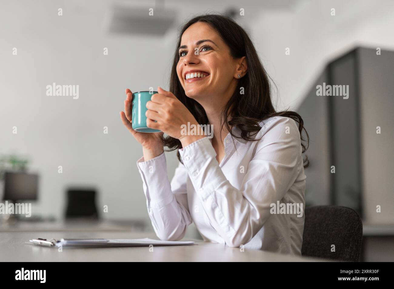 Cheerful and smiling young woman holding a cup of coffee Stock Photo