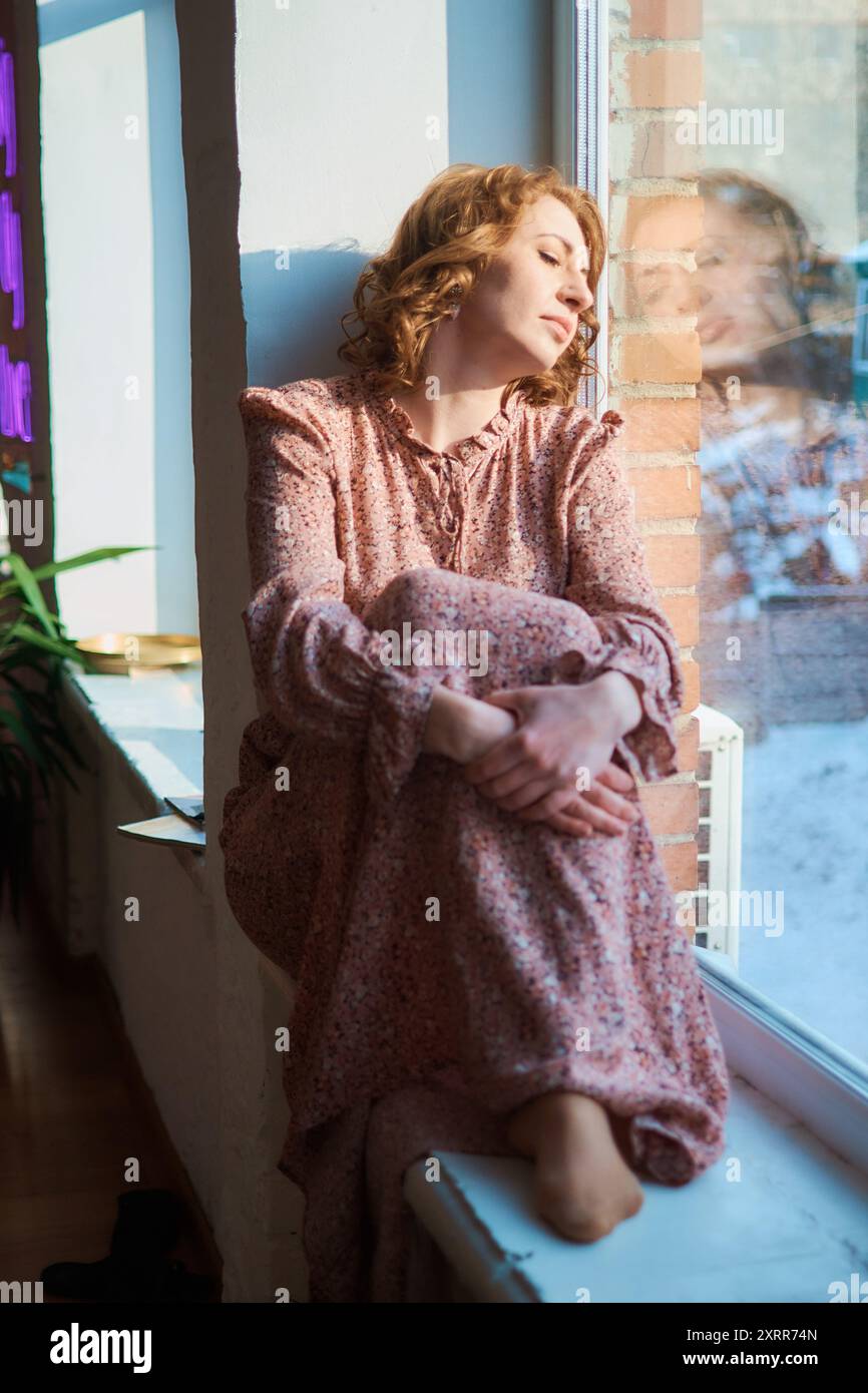 dreamy middle-aged woman by the window Stock Photo