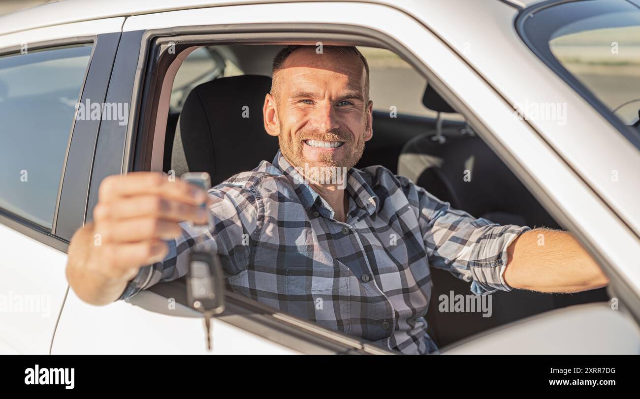 Attractive man holding keys against white car background Stock Photo ...