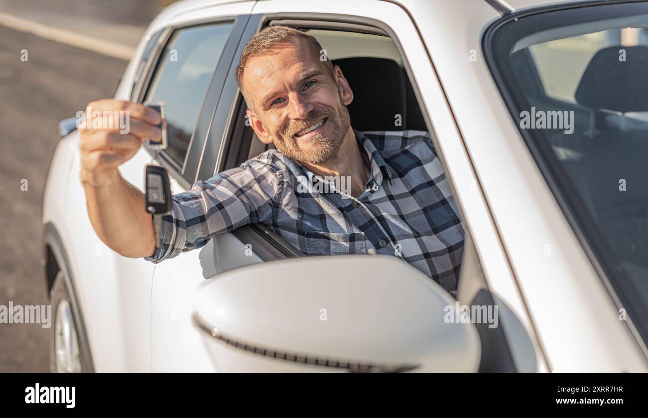 Attractive man holding keys against white car background Stock Photo ...