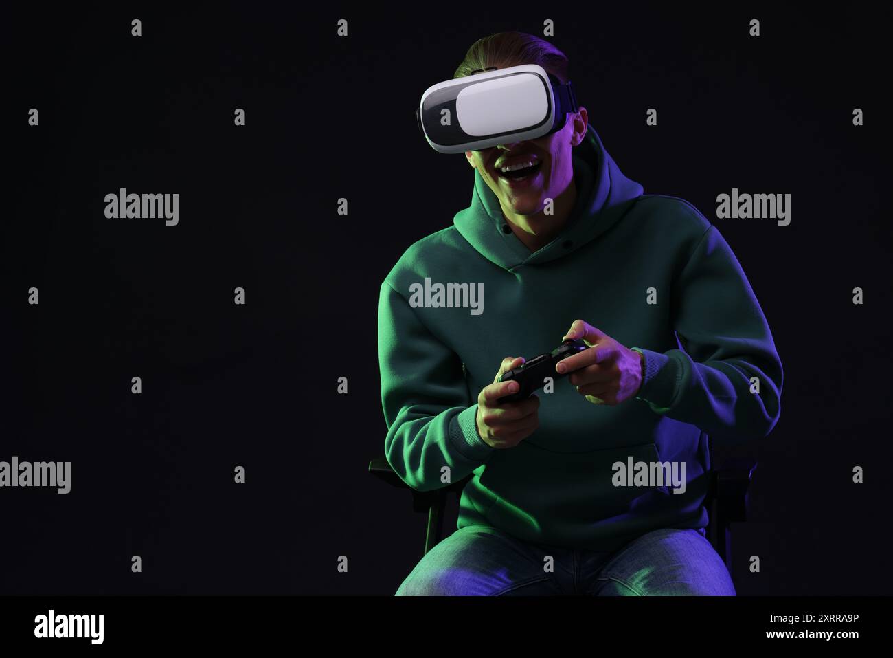 Happy young man with virtual reality headset and controller sitting on ...