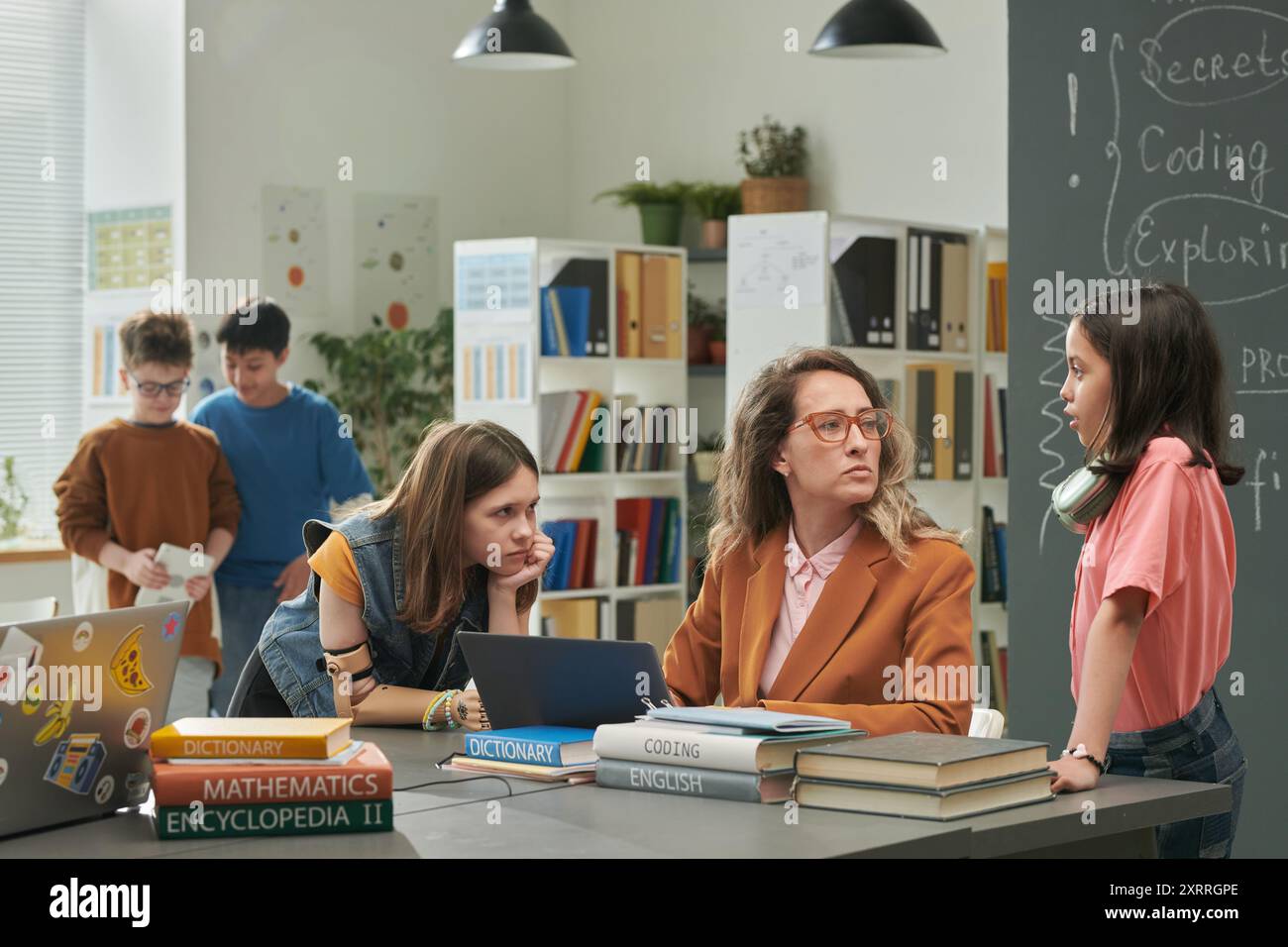 Teacher Talking to Girls in School Library Stock Photo - Alamy